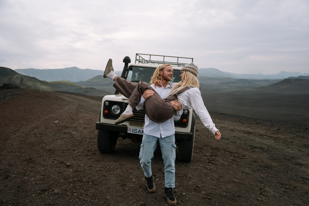 Groom carrying the bride in front of their adventure-ready Land Rover
