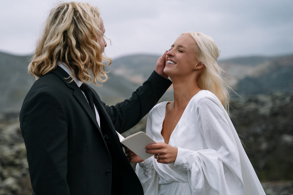 Couple exchanging vows in front of Iceland’s multicolored mountains during their hot springs elopement