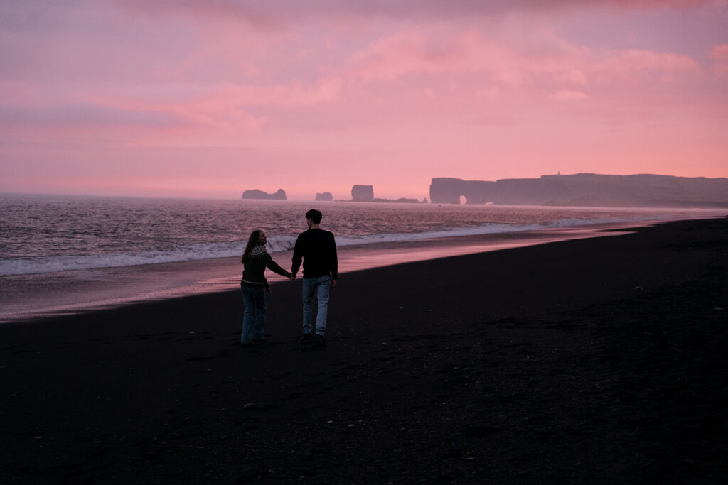 Couple standing on the black sand of Reynisfjara Beach during their Icelandic wedding weekend.