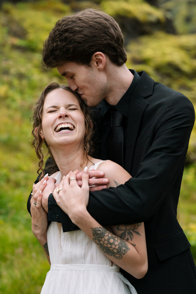 Close-up of bride and groom smiling in front of Skogafoss.