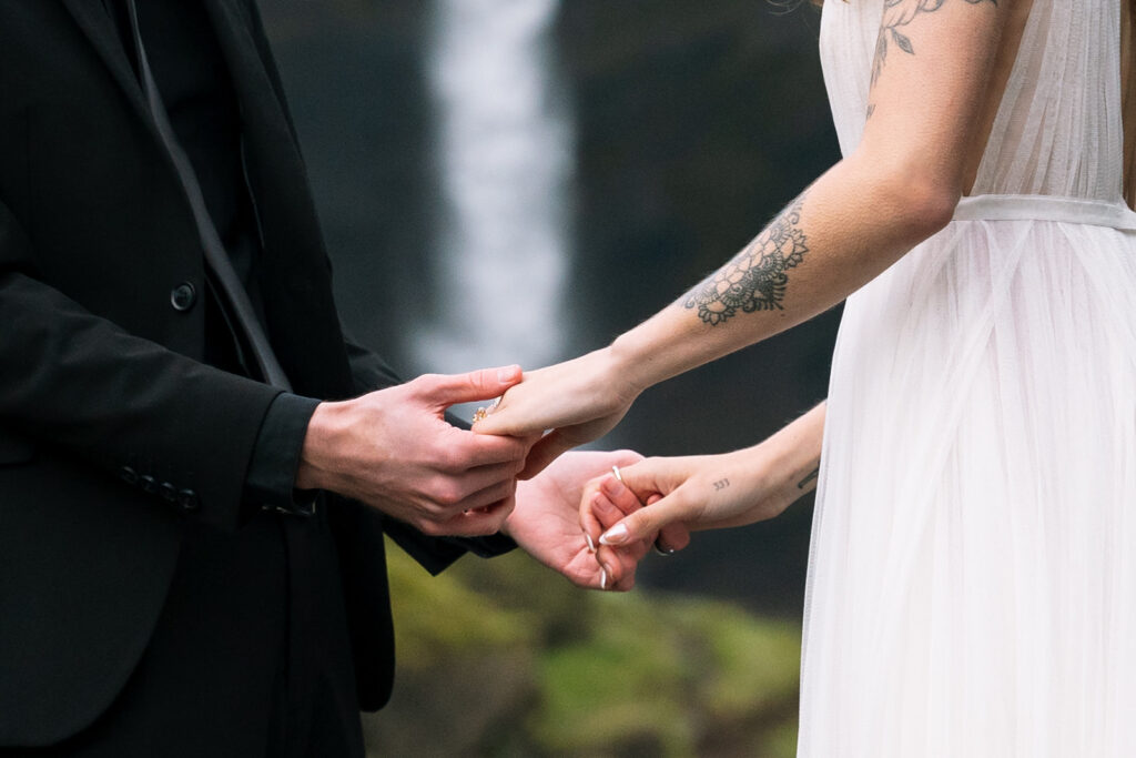 holding hands at Skogafoss waterfall during their Icelandic wedding.