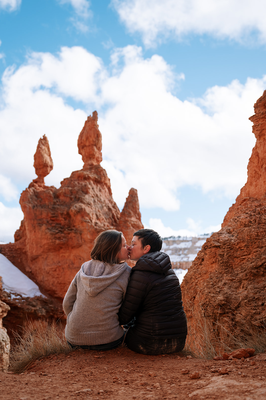 LGBTQ+ elopement photographer documents a kiss framed by Utah's iconic red hoodoos.